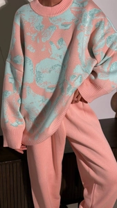 Detailed close-up of pink knit cuff and abstract floral jacquard pattern on the sweater