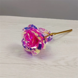 Close-up of artificial golden rose with iridescent foil petals on a wooden surface