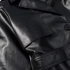 Close-up of lapel collar and round button on a black long faux leather trench coat