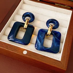 Minimalist geometric square earrings featuring blue resin drops and gold metal fittings