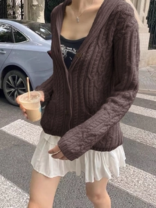 Detailed close-up of dark brown cable-knit texture on a long-sleeved buttoned cardigan