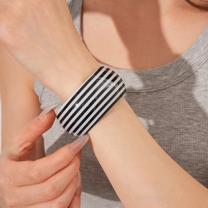 Close-up of wide black and white striped open bangle on a female model wrist