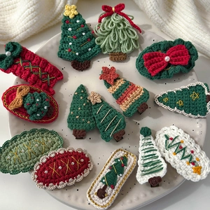 Handmade knitted Christmas hair clips featuring festive tree and bow designs on a ceramic tray