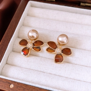 Macro view of amber flower stud earrings with pearl accents and sparkling zircon centers