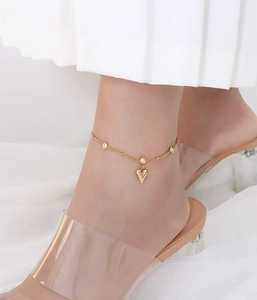 Close-up of a gold-plated heart anklet with clear zircons on a delicate bead chain