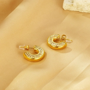 Detailed view of 18k gold plated C-shaped hoop earrings with crystals on champagne silk