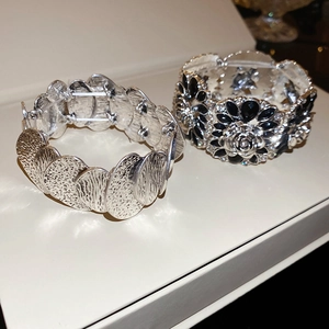 Close-up of vintage elastic bracelet featuring black gems and hammered silver metal petals