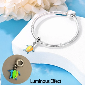 Glow-in-the-dark turtle charm on silver snake chain bracelet showing luminous effect