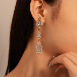 Gros plan de boucles d'oreilles géométriques avec strass brillants portées par un mannequin