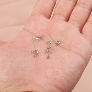 Silver metal crimp bead covers for DIY jewelry making held in a hand for size reference