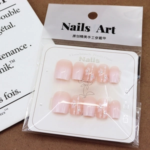 Pink and white gradient press-on nails with floral patterns and delicate rhinestones
