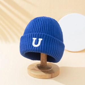Bonnet en maille côtelée bleu marine avec lettre U brodée sur un support en bois