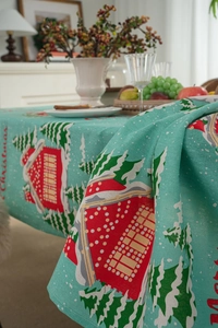 Detail of Christmas tablecloth fabric with printed houses, trees, and snowflake patterns