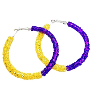 Close-up of oversized hoop earrings with purple and yellow glitter surface textures