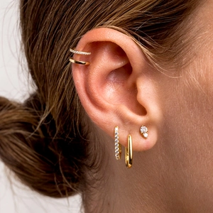 Detailed close-up of 18k gold-plated cuff earrings set with cubic zirconia on model ear