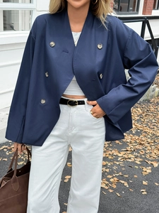 Detail of dark blue double-breasted coat paired with white trousers and black belt