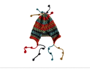 Detailed close-up of colorful striped knit beanie featuring long tassels and soft pompoms