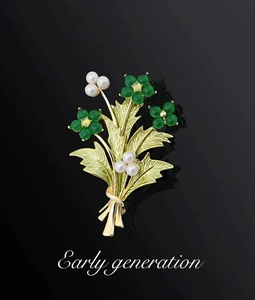 Dettaglio spilla a bouquet dorata con fiori verdi e perle bianche lucide