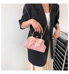 Sac à bandoulière en tweed rose avec nœud en soie et poignée dorée porté par un mannequin