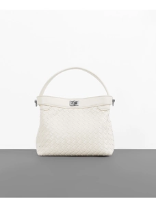 Macro detail of high-quality cream woven texture on a minimalist handbag handle