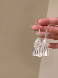 Détail de boucles d'oreilles à pompon argenté avec perles vert clair de style ethnique