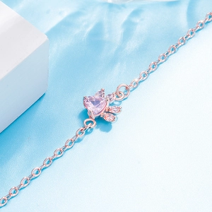 Macro detail of a rose gold cat paw bracelet featuring a pink heart-shaped stone and zircons