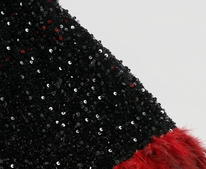 Close-up of black sequins and red feather trim on a luxury evening gown detail