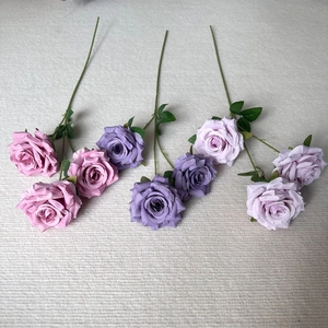 Close-up of artificial dusty pink and purple roses with realistic fabric petals texture