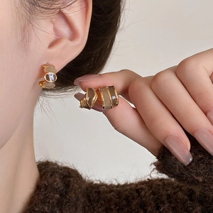 Fashionable C-shaped gold metal earrings with taupe resin inlay on female model