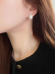 Detailed close-up of an elegant flower stud earring with pearls and sparkling crystals