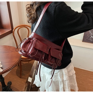 Detail of a dark red bow pleated shoulder bag in a retro cafe setting for style