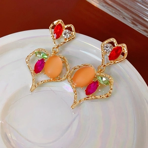 Primo piano di orecchini vintage a cuore con strass colorati e pietra occhio di gatto