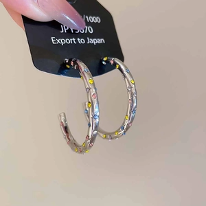 Vue détaillée de créoles argentées en forme de C serties de strass colorés