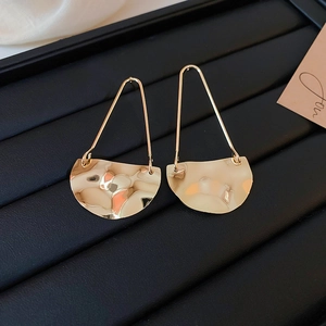 Detail of gold geometric earrings with hammered texture and triangular metal hooks