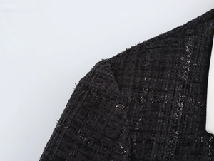 Gros plan sur la texture en tweed noir avec fils brillants et détails de couture d'épaule