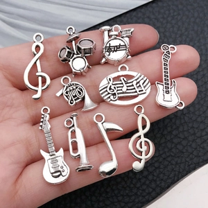 Detail of antique silver musical pendants including guitar and treble clef in hand