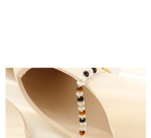 Detailed view of beaded bracelet with tiger eye and gold spacers on a beige stand