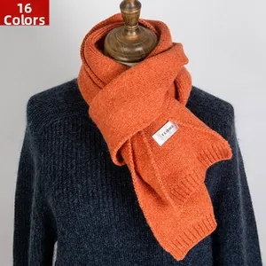 Detail of orange knitted scarf showing herringbone texture and white brand label logo
