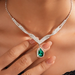 Close-up of a vintage teardrop green crystal necklace with micro-paved silver diamonds