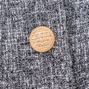 Women's tweed two-piece suit featuring black and white fabric and gold buttons