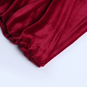 Dettaglio ravvicinato dei polsini plissettati e del tessuto di velluto rosso dell'abito