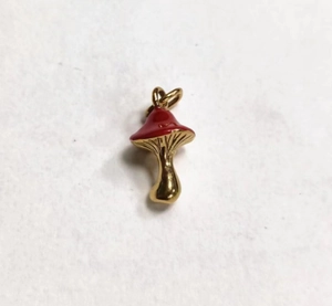 Detailed close-up of a red enamel mushroom pendant with a polished gold metal stem