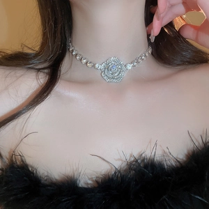 Close-up of sparkling camellia flower necklace with inlaid crystals on a model's collarbone