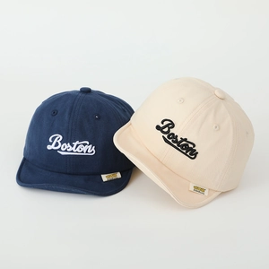 Close-up of cotton baby caps with Boston embroidery in navy blue and cream white