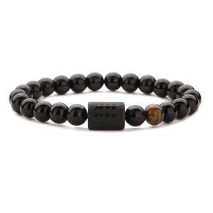 Detail of beaded men's bracelet with black obsidian, tiger eye stone and carved cylinder