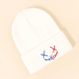 Détail du bonnet blanc à revers avec motif smiley brodé en rouge et bleu