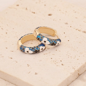 Detailed macro of gold-plated hoop earrings with blue enamel and floral patterns