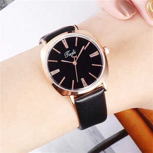 Close-up of a square rose gold quartz watch with a black leather strap on a female wrist