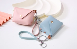 Close-up of mini PU leather keychain wallets in pink and blue with metal hardware