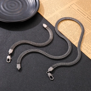 Detail shot of black snake chain necklace and bracelet set on vintage paper background